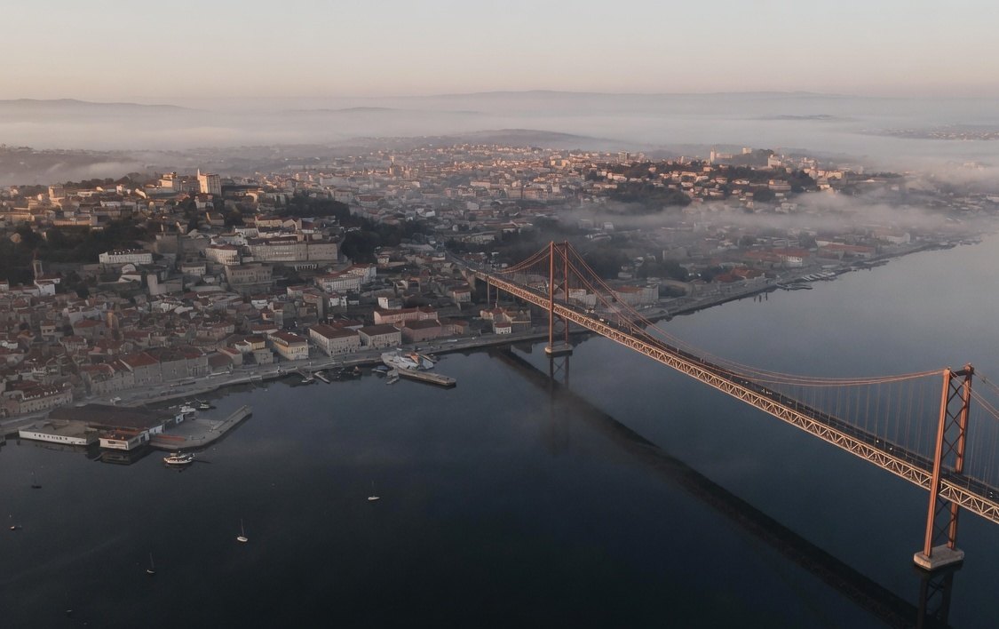 Aerial view of a harbour city and a long bridge at dawn